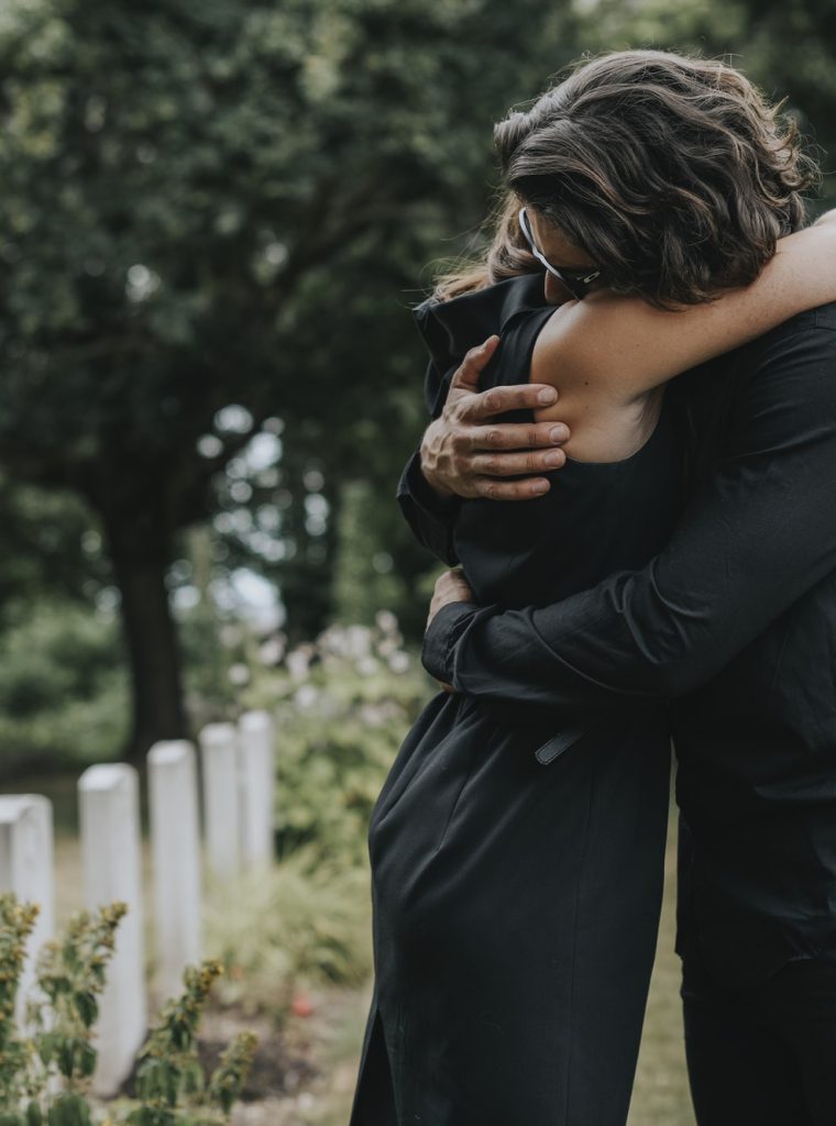 husband-trying-to-comfort-his-wife-at-a-graveyard.jpg